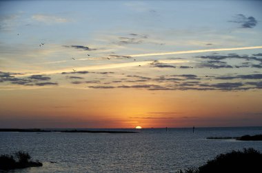 Güneş sakin okyanusun üzerinde yavaşça batar.