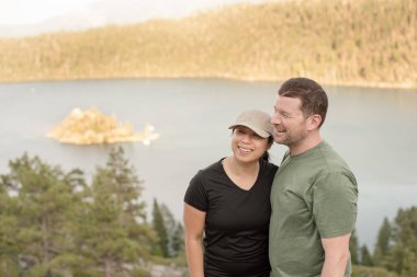 Zümrüt koyuna bakan çift birlikte gülüyor.