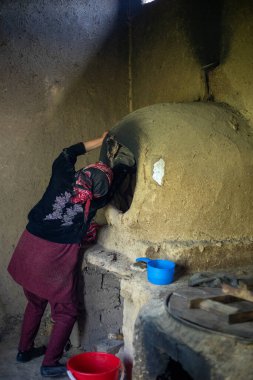 Bir kadın tuğla fırının önünde duruyor.