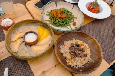 İçinde pirinç, et ve sebzeler bulunan üç kase yiyecek olan bir masa.