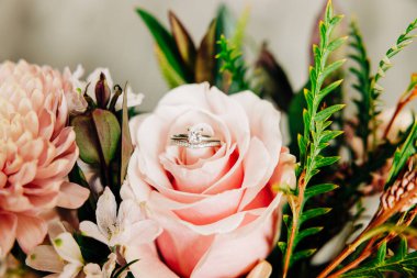 Pembe gülün üzerinde oturan alyansların makro fotoğrafı.