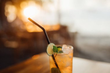 Kireç ve nane ile gün batımında tahta bir masa üzerinde ferahlatıcı içecek.