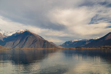 Dağ manzarası ve bulutlu gökyüzü göle yansıyor.
