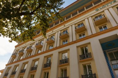 Üzerinde balkon ve yeşil tabela olan büyük bir bina.