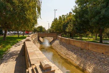 Taş kaplı bir kanalın içinden geçen tuğla bir duvar.
