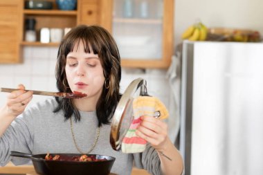 Genç bir kadın mutfakta yemek pişiriyor.