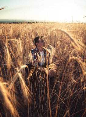 Genç adam güneş doğarken çiftliklerde oturuyor.