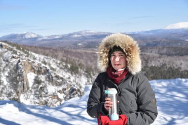 Genç adam karlı bir dağın tepesinde duruyor.