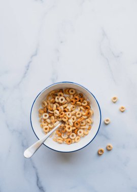 Bir kase Cheerios kahvaltı gevreği beyaz arka planda sütle.