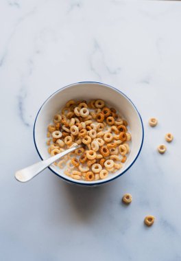 Bir kase Cheerios kahvaltı gevreği beyaz arka planda sütle.