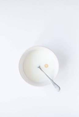 Beyaz arka planda tek amigolu mısır gevreği olan bir kase süt..