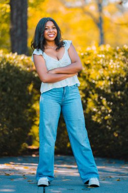 Parkta gülümseyerek poz veren bir genç.