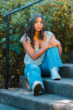 Parktaki merdivenlerde model yüzüyle poz veren bir genç.