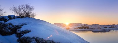 Karla kaplı tepe, bir su kütlesinin yanında.
