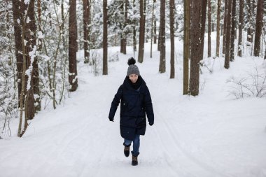 Karla kaplı çam ağaçları arasında koşan bir kadın.
