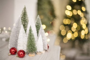 Parlak ışıkların önünde kırmızı süslemeli mini ağaçlar ormanı