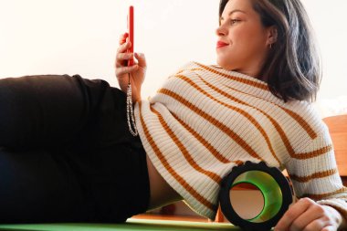 A woman is lying on a massage roller with a red phone in her hands clipart