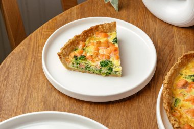 Beyaz tabakta somon ve brokoli turtası.