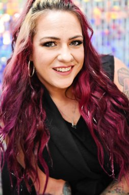 Smiling woman with vibrant pink hair and tattoos, close-up view. clipart