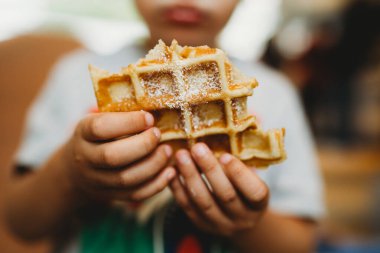Yedikleri waffle 'ı tutan genç ellere yakın durun.