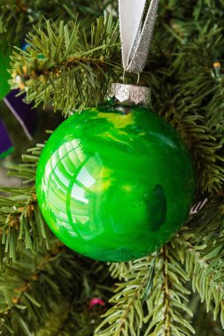 Green glossy ornament hanging on a Christmas tree clipart