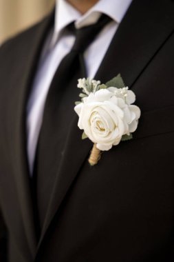 Damat yaka çiçekli yaka çiçeği giyiyor.