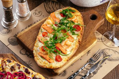 Deniz ürünleri soslu pizza, mozzarella peyniri ve roka.