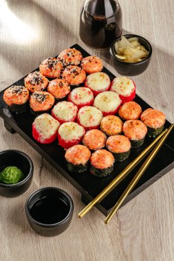 Soya sosu ve Çin yemek çubuklarıyla bir tabak suşi rulosu.