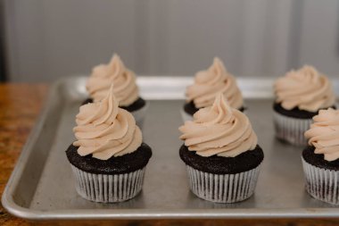 Up-close of chocolate cupcake on tray with frosting clipart