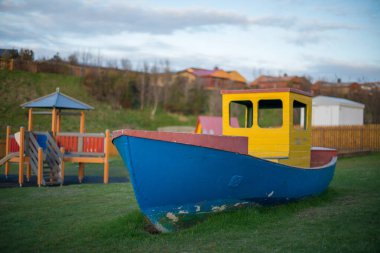 Colorful playground boat on a grassy field clipart