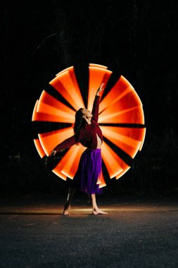 Woman in purple skirt posing in front of radiant orange light beams clipart