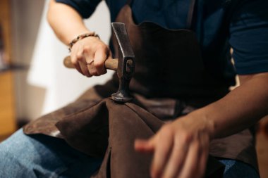 Ayrıntılı bir el yapımı sürecinde deri ustası çekiç materyali