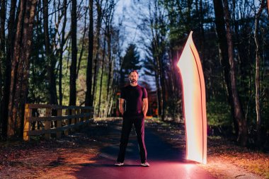 Man standing on a forest path with a glowing vertical light clipart