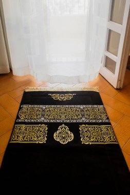 Pencerenin önündeki siyah İslam halısı