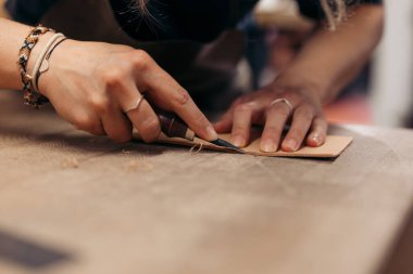 Leather artisan hand-carving edges for a handmade leather piece clipart