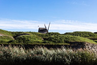Taş bir duvardaki ahşap yel değirmeni