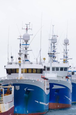 Fishing boats lined up at a snowy harbor clipart