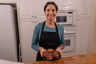 Kadın fırıncı mutfakta fıstık ezmeli kurabiye tabağı tutuyor.