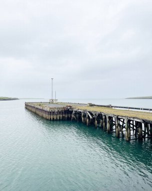 Sakin sularda iskele, bulutlu gökyüzü