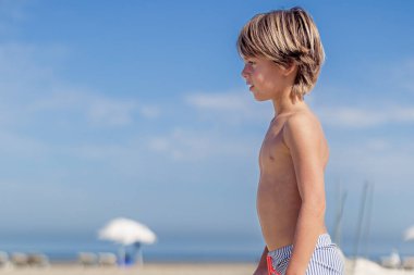 Sahilde duran genç bir çocuğun yan görüntüsü.