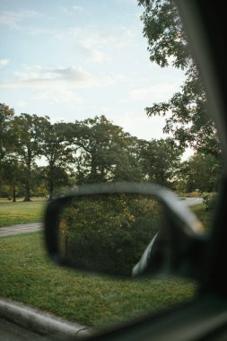 Araba yan aynası ağaçların yansıması ve parkta yürüyüş yolu.
