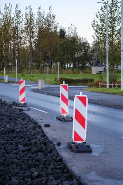 Yan tarafında kırmızı ve beyaz çizgili işaretler olan bir yol.
