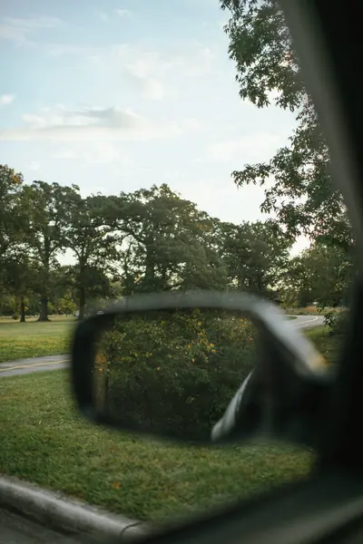 Araba yan aynası ağaçların yansıması ve parkta yürüyüş yolu.