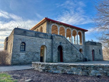 Kemerli pencereli, kırmızı çatılı, taş merdivenli tarihi taş bina.