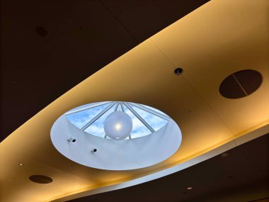 Çatı pencereli modern tavan, dairesel tasarım, alışveriş merkezinde sıcak ışıklandırma.