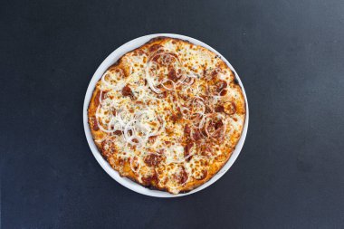 Siyah arka planda sosisli ve soğanlı İtalyan pizzası.