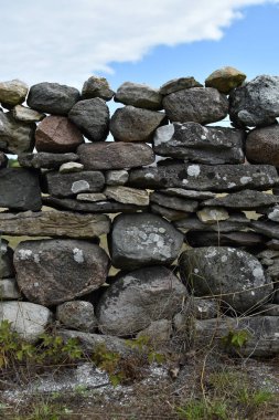 Kırsal taştan bir duvar, bir blu altında yeşil çimlerin arasında güçlü duruyor.