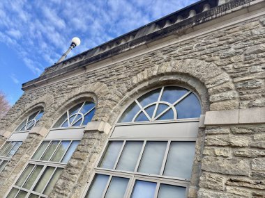 Mavi gökyüzünü yansıtan kemerli pencereli taş bina cephesi