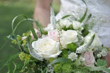 Gelin güzel bir buket beyaz ve pembe gül tutuyor.
