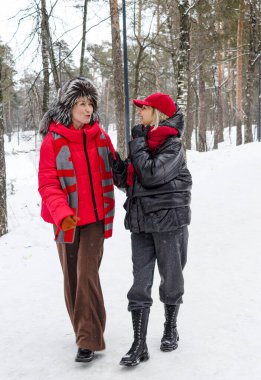 İki şık giyimli arkadaş kışın parkta yürürler.